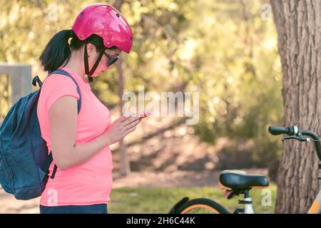 Jeune femme effectuant un paiement en ligne avec son téléphone portable pour une location de vélos Banque D'Images