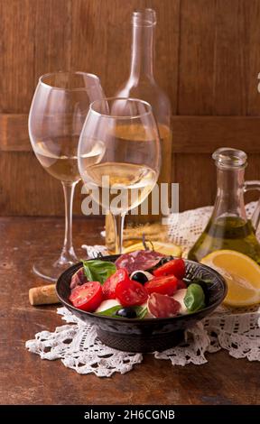 Vin et tomates au basilic dans un décor vintage sur une table en bois Banque D'Images