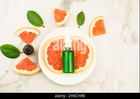 une bouteille de pamplemousse essentiel sur une plaque blanche et une table en marbre. pamplemousse naturel, vitamine c. vue du dessus Banque D'Images