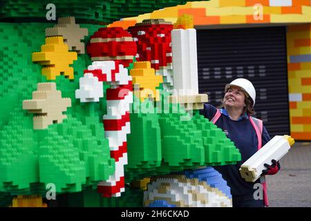 Paula Laughton, chef de la création de modèles, apporte la touche finale à un arbre de Noël LEGO de 33 mètres de haut, fabriqué avec 364,481 briques DUPLO et LEGO, au LEGOLAND Windsor Resort de Berkshire.Date de la photo: Mercredi 10 novembre 2021. Banque D'Images