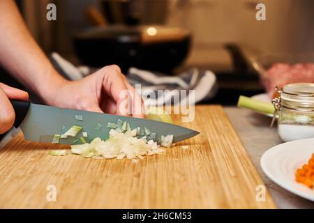 Une femme avec un couteau coupe l'oignon sur des tranches pour la cuisson Banque D'Images