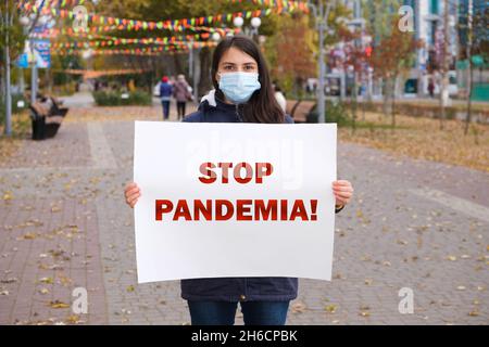 Une femme dans un masque médical tient une affiche qui dit Stop Pandemia Banque D'Images