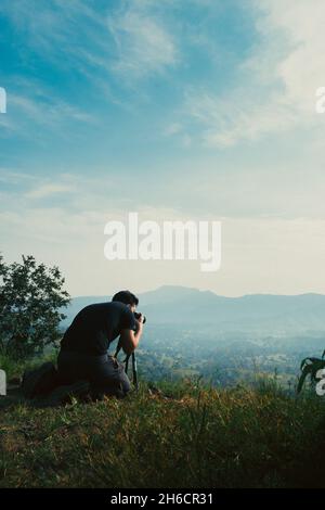 Un photographe prenant une photo de paysage sur son appareil photo monté sur un trépied Banque D'Images