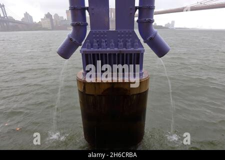 Les tuyaux d'évacuation par temps humide entraînent le ruissellement et la pollution de l'autoroute FDR, y compris la quinone-6PPD, dans la rivière East lors d'une tempête de pluie à New York. Banque D'Images