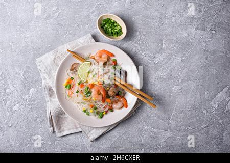 Vue de dessus de l'assiette avec haricots japonais ou nouilles de verre, crevettes savoureuses, champignons shiitake et légumes sur fond de béton gris Banque D'Images