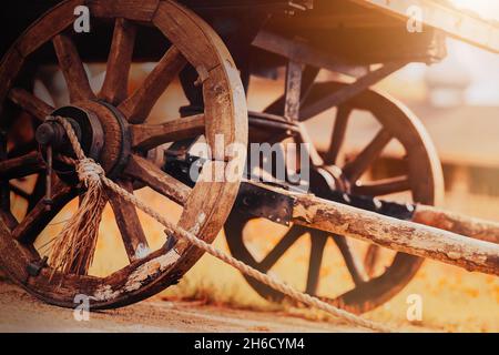 Une vieille charrette en bois avec de grandes roues se dresse sur la route dans le village par une journée ensoleillée d'automne.Chariot de récolte et agriculture.La paysannerie.Historique Banque D'Images