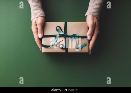 Les femmes tiennent une boîte cadeau de Noël avec ruban de velours attaché sur fond vert. Banque D'Images
