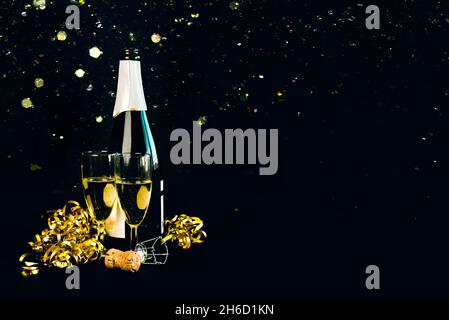 Bonne Année.Bouteille de champagne avec deux verres, banderoles dorées et paillettes étincelantes avec espace pour le texte sur fond noir.cele de la Saint-Sylvestre Banque D'Images
