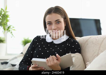 Brunette jolie femme lisant sur une histoire de fiction de canapé Banque D'Images