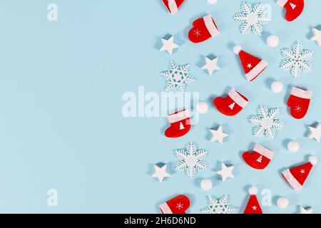 Couvre-lit de Noël avec chapeaux de père noël rouges, gants d'hiver et chaussettes avec étoiles et flocons de neige sur fond bleu avec espace de copie Banque D'Images