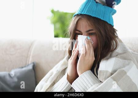 Une femme essuie le nez mouillé avec un mouchoir habillé de vêtements chauds à cause du froid Banque D'Images