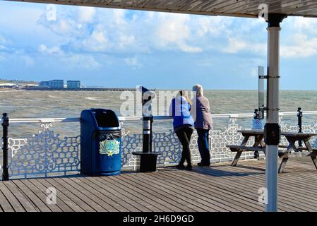 Vue arrière d'un couple sur Palace Pier, en direction de Brighton Marina, lors d'une journée automnale ensoleillée et venteuse, Brighton East Sussex, Angleterre, Royaume-Uni Banque D'Images