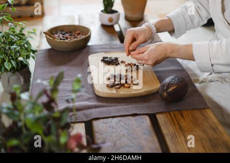 Les mains épluchant des haricots cacao bio sur une table en bois, des pointes de cacao, la fabrication artisanale de chocolat dans un style rustique pour la cérémonie sur la table.Dégustation Banque D'Images