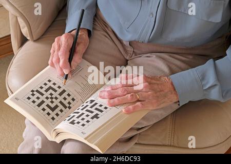 Mains d'une dame senior qui fait un puzzle à mots croisés Banque D'Images