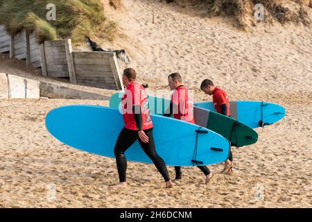 Un groupe de surfeurs masculins rentrant leurs planches de surf embauchées à la boutique de location de surf de Fistral à Newquay en Cornouailles. Banque D'Images