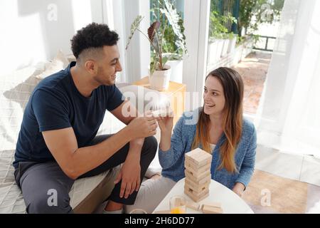 Joyeux jeune couple divers appréciant jouer à des jeux de société à la maison Banque D'Images