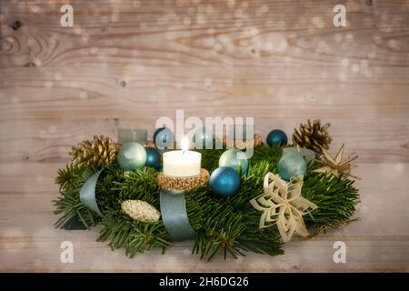 Série de couronnes de l'Avent numéro un avec une bougie allumée, boules de Noël bleues et décoration sur un fond de bois rustique enneigé, quatrième dimanche, copie de la flèche Banque D'Images