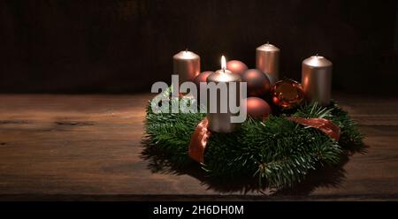 Première couronne de l'Avent avec bougies couleur cuivre et boules de Noël sur une table rustique en bois sur fond brun foncé, sélectionnée FO Banque D'Images