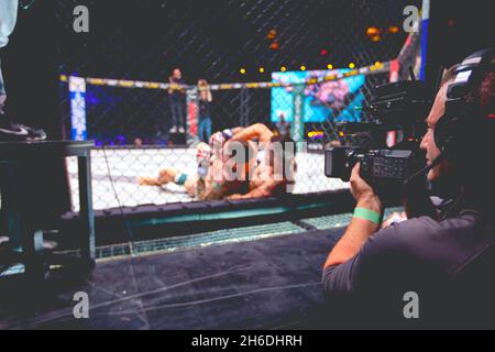 Caméraman professionnel, vidéaste filme avec caméra pour diffusion en direct MMA Fighters comme combat dans les combats sans règles dans l'octogone d'anneau. Banque D'Images