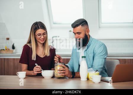 Photo d'un jeune couple heureux prenant le petit déjeuner dans le confort de leur maison Banque D'Images