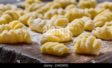 Gnocchi de pommes de terre crus faits maison avec farine et parmesan râpé sur planche à découper en bois.Macro, mise au point sélective Banque D'Images