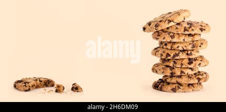 Bannière de la journée avec de délicieux biscuits aux pépites de chocolat fraîchement cuites dans une grande pile, à côté d'une mangée partiellement avec de la chapelure isolée sur le caramel b Banque D'Images