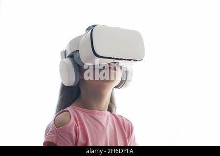 La fille a du plaisir dans les lunettes de réalité virtuelle, debout sur un fond blanc.Copier l'espace.Photo de haute qualité Banque D'Images