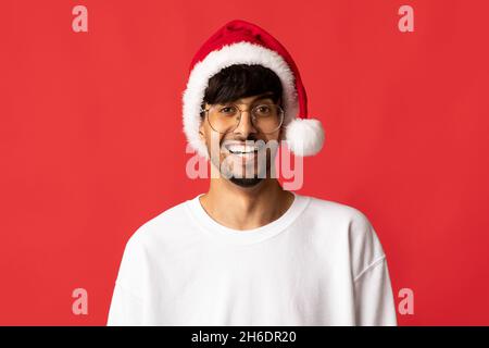 Portrait d'un homme indien charmant et joyeux en chapeau de père Noël Banque D'Images