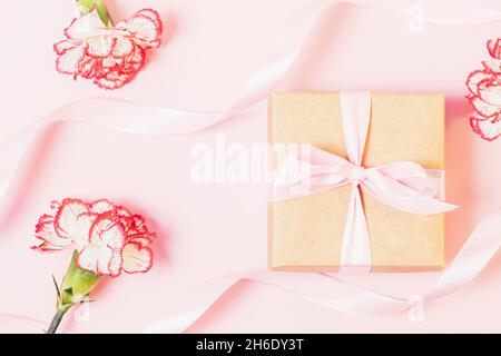 Composition Saint-Valentin avec boîte cadeau et belles fleurs sur fond rose clair, plat Banque D'Images