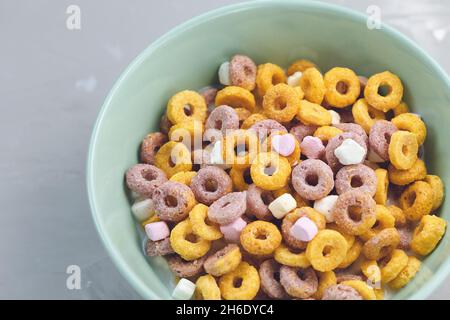 Plusieurs boucles de fruits de céréales colorées dans un bol sur fond gris. Gros plan, espace de copie. Concept petit déjeuner Banque D'Images