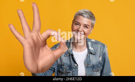 Bonne femme mûre montrant un geste correct et souriant à l'appareil photo Banque D'Images