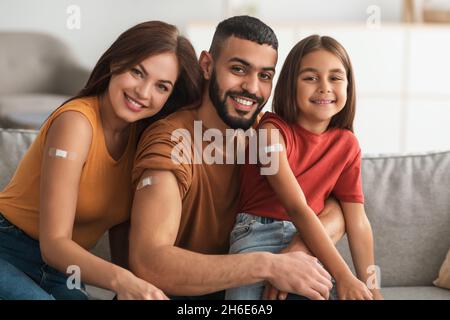 Bonne famille arabe vaccinée montrant bande adhésive après injection Banque D'Images