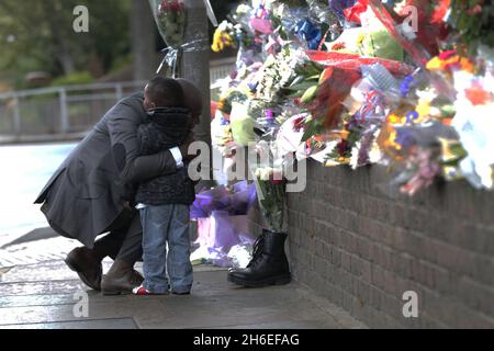 Un homme et son fils ont placé une rose à l'intérieur d'une paire de bottes de soldats laissées sur les lieux à Woolwich où le batteur Lee Rigby a été assassiné lors d'une attaque terroriste. Banque D'Images