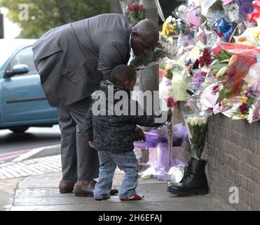 Un homme et son fils ont placé une rose à l'intérieur d'une paire de bottes de soldats laissées sur les lieux à Woolwich où le batteur Lee Rigby a été assassiné lors d'une attaque terroriste. Banque D'Images