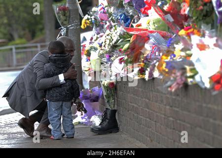 Un homme et son fils ont placé une rose à l'intérieur d'une paire de bottes de soldats laissées sur les lieux à Woolwich où le batteur Lee Rigby a été assassiné lors d'une attaque terroriste. Banque D'Images