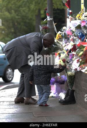 Un homme et son fils ont placé une rose à l'intérieur d'une paire de bottes de soldats laissées sur les lieux à Woolwich où le batteur Lee Rigby a été assassiné lors d'une attaque terroriste. Banque D'Images