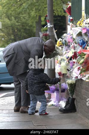 Un homme et son fils ont placé une rose à l'intérieur d'une paire de bottes de soldats laissées sur les lieux à Woolwich où le batteur Lee Rigby a été assassiné lors d'une attaque terroriste. Banque D'Images