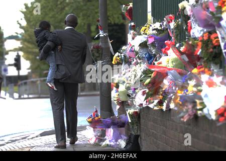 Un homme et son fils ont placé une rose à l'intérieur d'une paire de bottes de soldats laissées sur les lieux à Woolwich où le batteur Lee Rigby a été assassiné lors d'une attaque terroriste. Banque D'Images