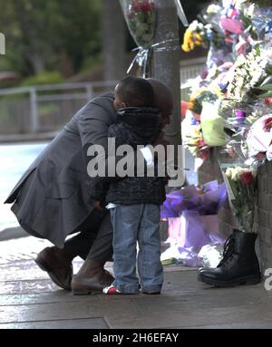 Un homme et son fils ont placé une rose à l'intérieur d'une paire de bottes de soldats laissées sur les lieux à Woolwich où le batteur Lee Rigby a été assassiné lors d'une attaque terroriste. Banque D'Images