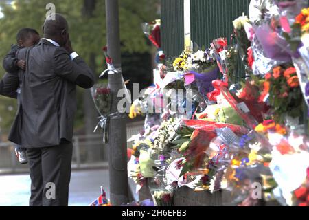 Un homme et son fils ont placé une rose à l'intérieur d'une paire de bottes de soldats laissées sur les lieux à Woolwich où le batteur Lee Rigby a été assassiné lors d'une attaque terroriste. Banque D'Images