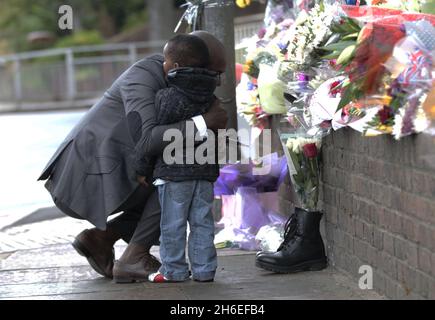 Un homme et son fils ont placé une rose à l'intérieur d'une paire de bottes de soldats laissées sur les lieux à Woolwich où le batteur Lee Rigby a été assassiné lors d'une attaque terroriste. Banque D'Images