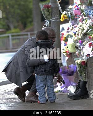 Un homme et son fils ont placé une rose à l'intérieur d'une paire de bottes de soldats laissées sur les lieux à Woolwich où le batteur Lee Rigby a été assassiné lors d'une attaque terroriste. Banque D'Images