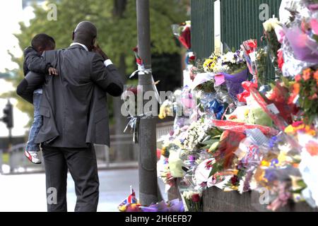 Un homme et son fils ont placé une rose à l'intérieur d'une paire de bottes de soldats laissées sur les lieux à Woolwich où le batteur Lee Rigby a été assassiné lors d'une attaque terroriste. Banque D'Images