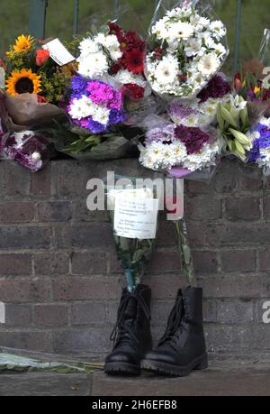 Un homme et son fils ont placé une rose à l'intérieur d'une paire de bottes de soldats laissées sur les lieux à Woolwich où le batteur Lee Rigby a été assassiné lors d'une attaque terroriste. Banque D'Images