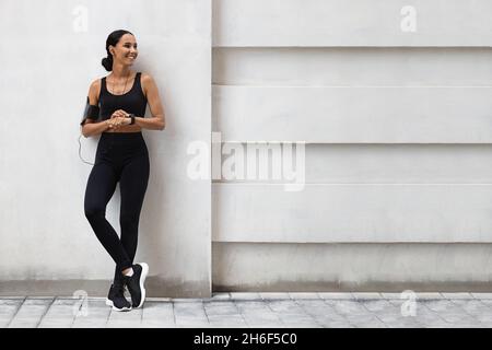 Publicité fitness.Athletic Lady dans le style Sportswear debout à l'extérieur près de Urban Wall Banque D'Images