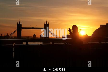 Les employés de la ville traversent le pont de Londres ce matin au printemps, comme le temps jusqu'à une journée incertaine à la Bourse. Banque D'Images