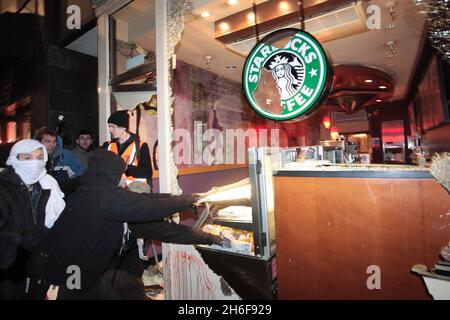 Les fenêtres d'une succursale de café Starbucks sont écrasées lors d'une manifestation contre le conflit à Gaza près de l'ambassade israélienne à Londres.Une manifestation pacifique a d'abord pris fin avec un groupe de manifestants face à la police anti-émeute montée qui lançait des missiles et fracassaient des fenêtres sur Kensington High Street, près de l'ambassade israélienne. Banque D'Images