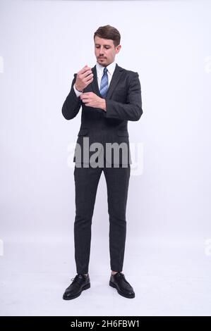 Pleine longueur Portrait d'élégant jeune homme d'affaires caucasien beau en costume formel debout isolé sur fond blanc en studio. Banque D'Images