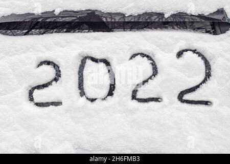 Le numéro 2022 est le symbole du nouvel an prochain, écrit de la neige fraîchement tombée qui se trouve sur le pare-brise de la voiture Banque D'Images