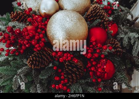 Décoration de Noël festive avec des boules dorées de Noël, des baies rouges et des cônes de forêt.Fête des vacances d'hiver.Concept de la nouvelle année. Banque D'Images